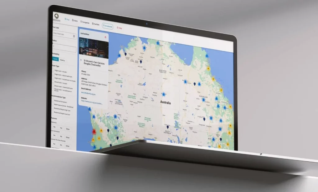 A laptop displaying a digital map of Australia with various colored markers and a sidebar showing data and options on the left side of the screen.